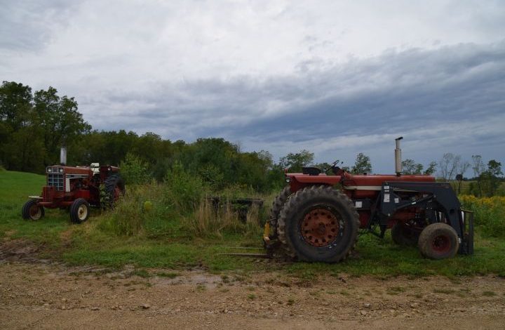 Two red tractors under a stormy sky