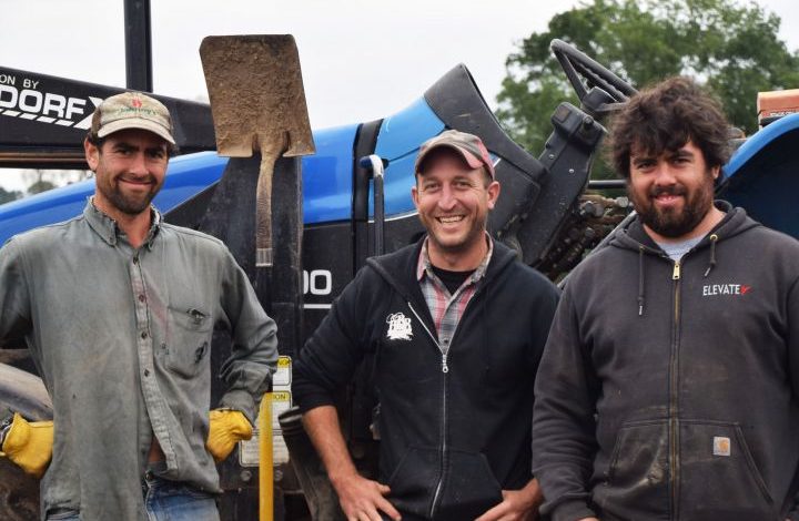 Three farmers in front of a tractor