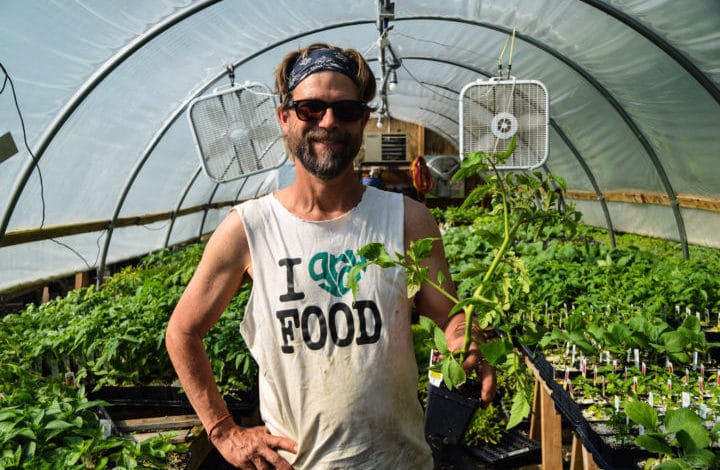 Mark Voss standing in a hoop house wearing a T shirt that reads I Grow Food